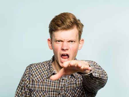 i send you rays of hatred. daunting frightening fearsome angry man reaching out his hand. portrait of a young guy on light background. emotion facial expression. feelings and people reaction.の写真素材