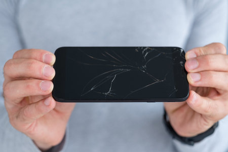 smashed shattered cracked screen. man holding damaged smart phone. mobile devices repair service...