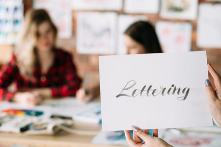 lettering art and calligraphy craft. italic cursive handwriting courses. woman hands holding paper...