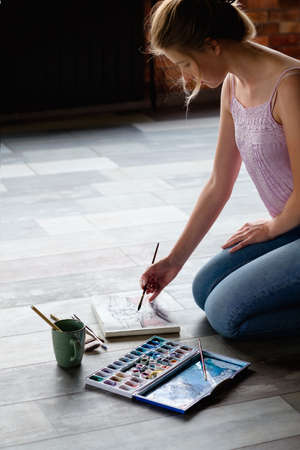 creative leisure. painting hobby. artful personality. talented girl drawing a picture sitting on the floor.の写真素材
