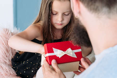 family traditions and holiday celebration. father presenting a gift box to daughter. daddys little princess gets a reward on her birthday or festive occasion. love care and appreciation.の写真素材