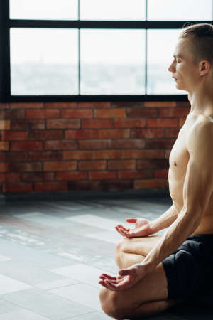 yoga instructor. fitness trainer. sport and athletic lifestyle. concentrated serene fit toned and muscular male teacher meditating.の写真素材