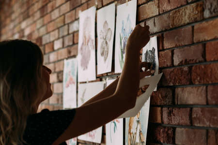 creative leisure. painting hobby. artful personality. talented girl sticking her watercolor drawings to the wallの写真素材