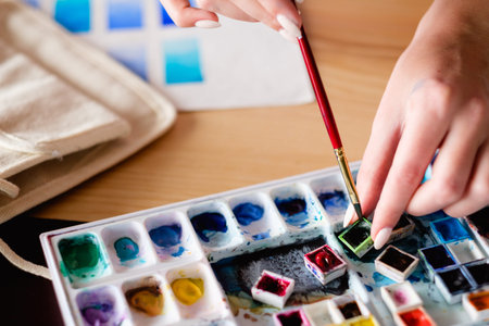watercolor palette. artist tools instruments and inks for creative leisure. painting lessons concept. woman loading brush with color.の写真素材