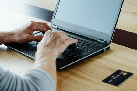 online income. work on the internet and earn money from home. man hands typing on the laptop. credit or debit card on the tableの写真素材