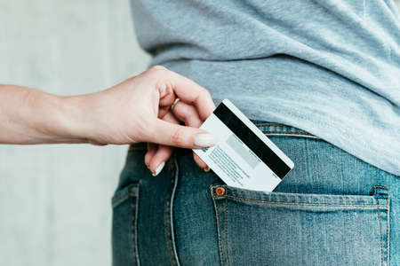 bank fraud. dangers of electronic money management. online credit card theft. hand stealing bank card from mans pocket.の写真素材