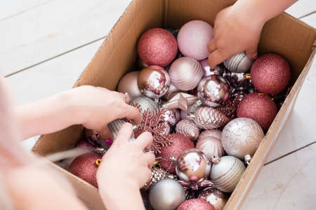 happy christmas traditions of home and fir tree decoration, women choosing the best adornments from a box with new year balls and toys mix.の写真素材