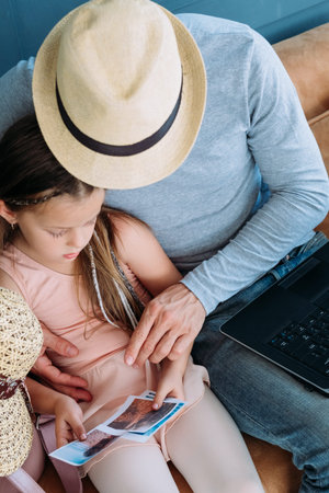 summer travel memories and experiences. dad and his daughter looking through printed photos from their vacation tour at the seaside. summer holidays and adventures concept.の写真素材