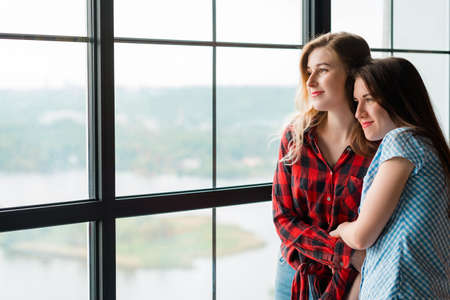 friendship or family relationship. two bff girlfriends or sisters looking out the window. love trust comfort. leisure and pastime concept.の写真素材