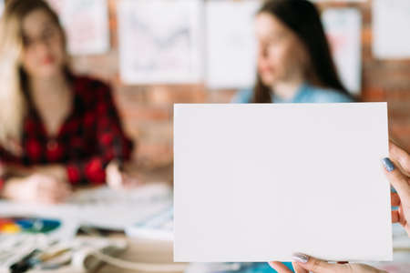 art painting leisure craft and drawing hobby. lettering courses or calligraphy classes. woman holding a blank sheet of white paper. empty space for advertisement.の写真素材