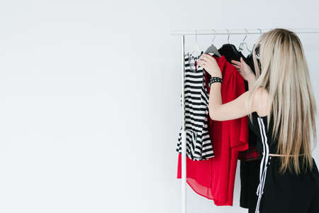 clothes designer. fashion industry and creative hobby turned into business concept. woman organizing colorful clothing items from her new collection hanging on the racks.の写真素材