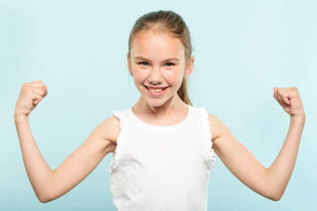 emotion expression. victory yes. very happy joyful thrilled to bits child with beaming smile and hands in the air. young cute girl portrait on blue background.の写真素材