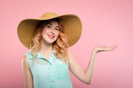 happy smiling joyful pleased woman in huge sunhat holding virtual object in hand. summer skincare...
