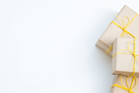 christmas presents in gift boxes wrapped in craft paper and tied with a yellow twine. three packages...