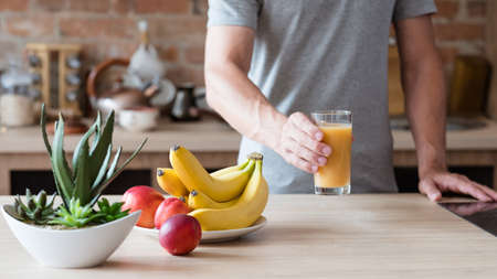 healthy eating habit. unrecognizable man holding a glass of freshly squeezed fruit juice. natural organic banana and nectarine drink. balanced diet and nutrition.の写真素材