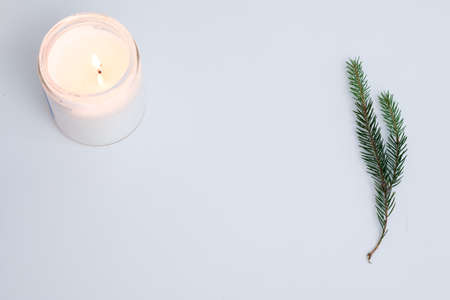 seasonal minimalistic background. fir tree branches and burning candle on white background. simple new year natural decor. free space concept.の写真素材