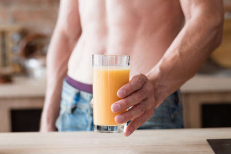 detox diet drink for slimming and weightloss. sexy fit muscled bare chested unrecognizable man holding a glass of healthy beverageの写真素材