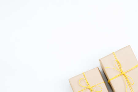 holiday presents in gift boxes wrapped in craft paper and tied with a yellow twine. two packages on white background with copyspace.の写真素材