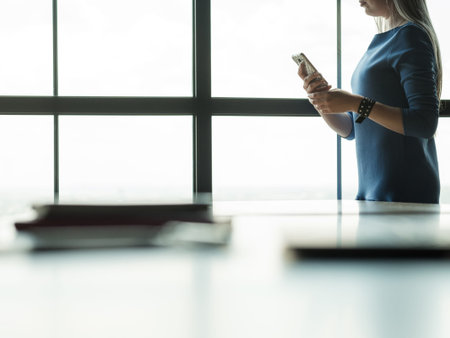 business communication. woman using her mobile phone in office workspace messaging partners or...