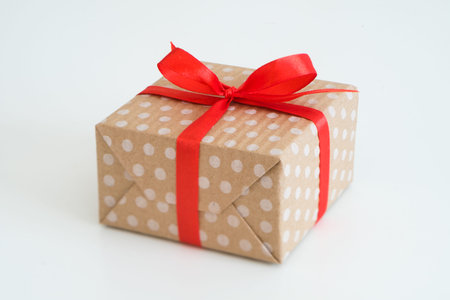new year present in gift box wrapped in craft dotted paper and tied with a red ribbon bow. package...