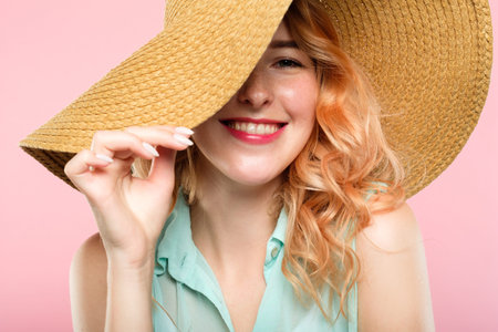 emotion expression. smiling happy woman pleased with herself. self-satisfied young beautiful girl in a sunhat. summer beauty and fashion concept. portrait on pink background.の写真素材