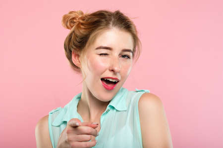 emotion expression. smiling woman pleased with herself. young beautiful girl winking. portrait on pink background.の写真素材