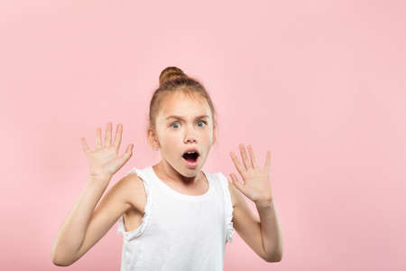 surprised astonished amazed girl gasping from shock. unbelievable news. young cute child on pink background. emotional facial expression.の写真素材
