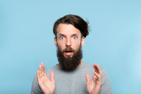 omg unbelievable shock amazement. dumbfounded man with open mouth. portrait of a young bearded guy on blue background. emotion facial expression and reaction concept.の写真素材