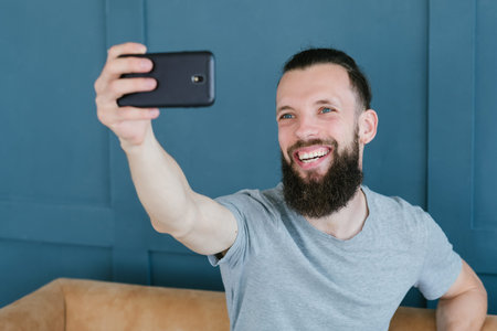 blogger streaming live using mobile phone. bearded hipster man communicating with subscribers...
