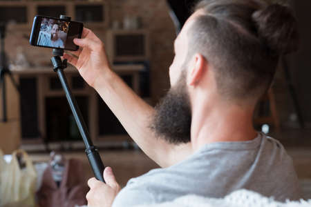 bearded hipster man taking a selfie using phone camera on a stick. idle leisure and relaxed carefree lifestyle. modern technology and social media addiction concept.の写真素材