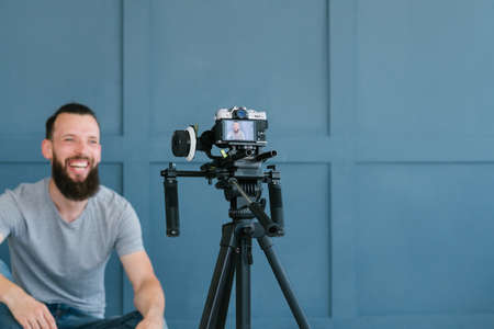 content creation for social media. bearded man shooting video of himself using camera on tripod. modern technology and blogging freelance work concept.の写真素材
