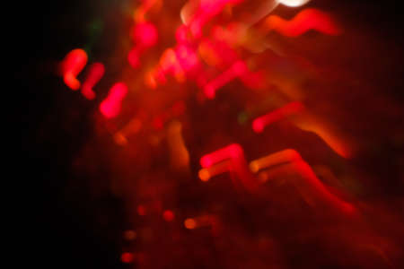 abstract lens flare on black background. red defocused bokeh lights. glowing blurred color burst. festive new year backdrop.の写真素材