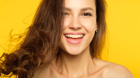 emotion face. smiling laughing woman pleased with herself. self-satisfied young beautiful brown haired girl. portrait on yellow background.の写真素材