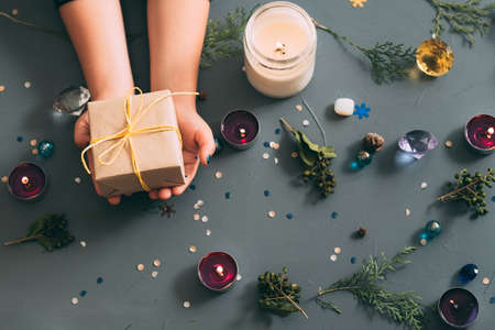 new year magic atmosphere and holidays festivity. assortment of decor elements on blue background. hands holding gift box.の写真素材