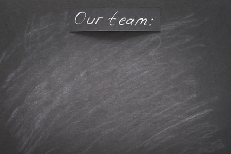 our team written on black chalkboard. empty space for list on names.の写真素材