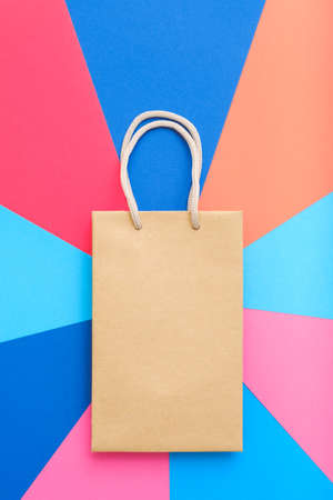 craft paper shopping bag on multicolor geometric background. gifts and presents buying. copy space concept.の写真素材