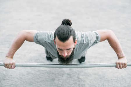 wide grip bar push ups. sport and fitness. man exercising outdoor. chest muscles training.の写真素材