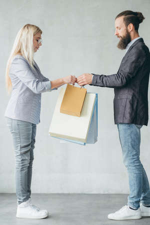 shopping and store delivery. man giving multiple bags to a woman.の写真素材