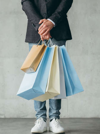 black friday shopping. store sales and discounts. man holding multiple bags with goods in hands.の写真素材