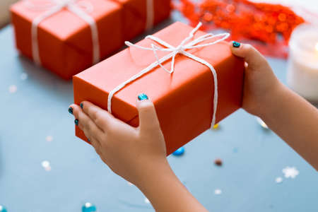 new year present in red paper wrapping. hands holding a gift box. greeting surprise and reward concept.の写真素材