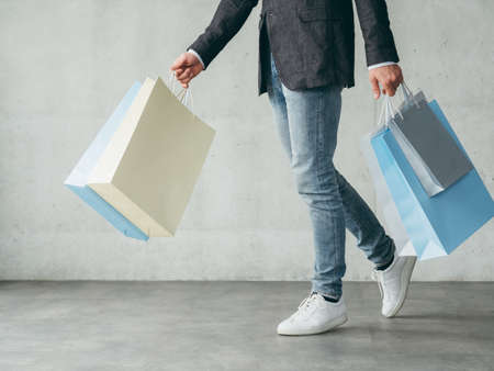 shopping hobby. cheery man fashionist walking and holding multiple bags with new outfits.