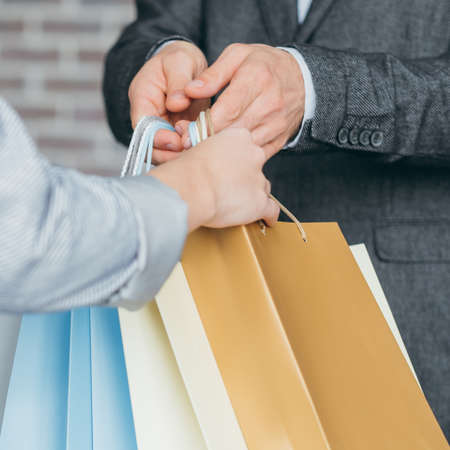 store checkout. shopping and consumerism concept. woman taking her purchases from cashier.の写真素材