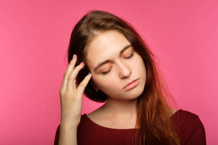 tired sad young woman. portrait of a sleepy drowsy and exhausted pretty girl on pink background.の写真素材