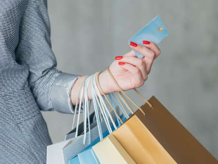 money loan for shopping. woman holding credit card and multiple bags in her hand.の写真素材