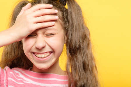 laughing girl embarrassed with her silliness cover forehead with hand. facepalm failure and shame concept.の写真素材