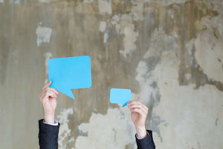 empty speech bubble papers in man hands. feedback communication dialogue discussion concept.の写真素材