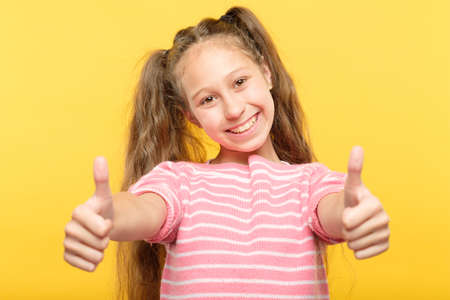 smiling child showing two thumbs up. success and approval concept.の写真素材