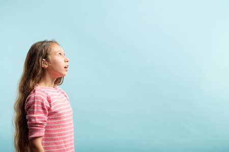 amazed shocked young girl looking up at a virtual object or text speech bubble. empty space for...