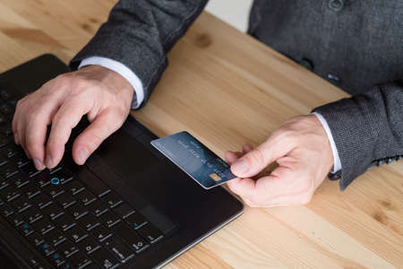 online payment. man typing data from his credit card on the laptop.