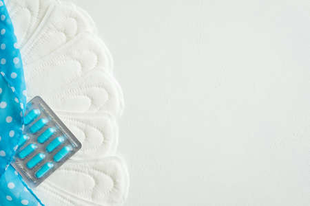 panty liners and painkillers for menstrual period pain on white background. medicine pills and...